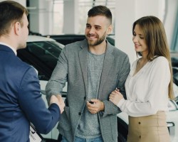 Un vendeur conseillant un couple dans une concession automobile