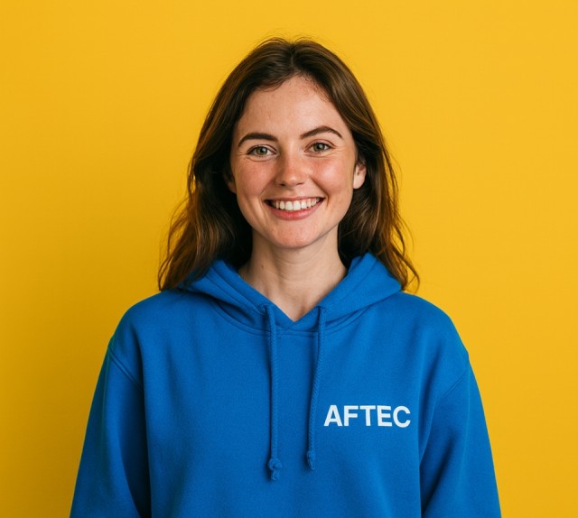 jeune étudiante de 25 ans portant un sweat à capuche bleu avec le logo AFTEC sur un fond jaune